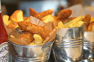 Freshly cooked chunky Fish bites and Chips from Fruits & Fountains in stainless steel serving pails